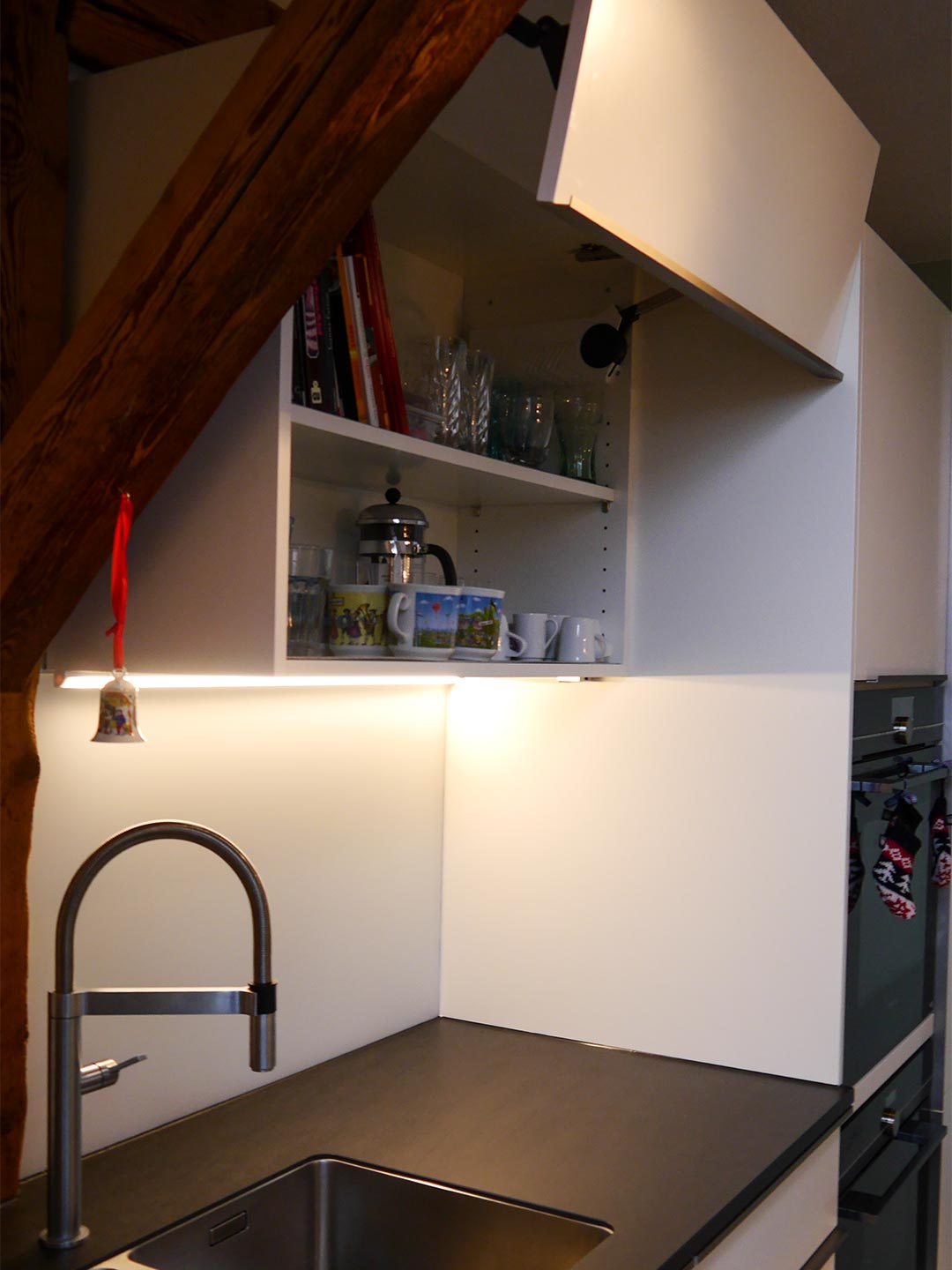 Der Hängeschrank mit LED-Beleuchtung ist exakt ins Gebälk eingepasst