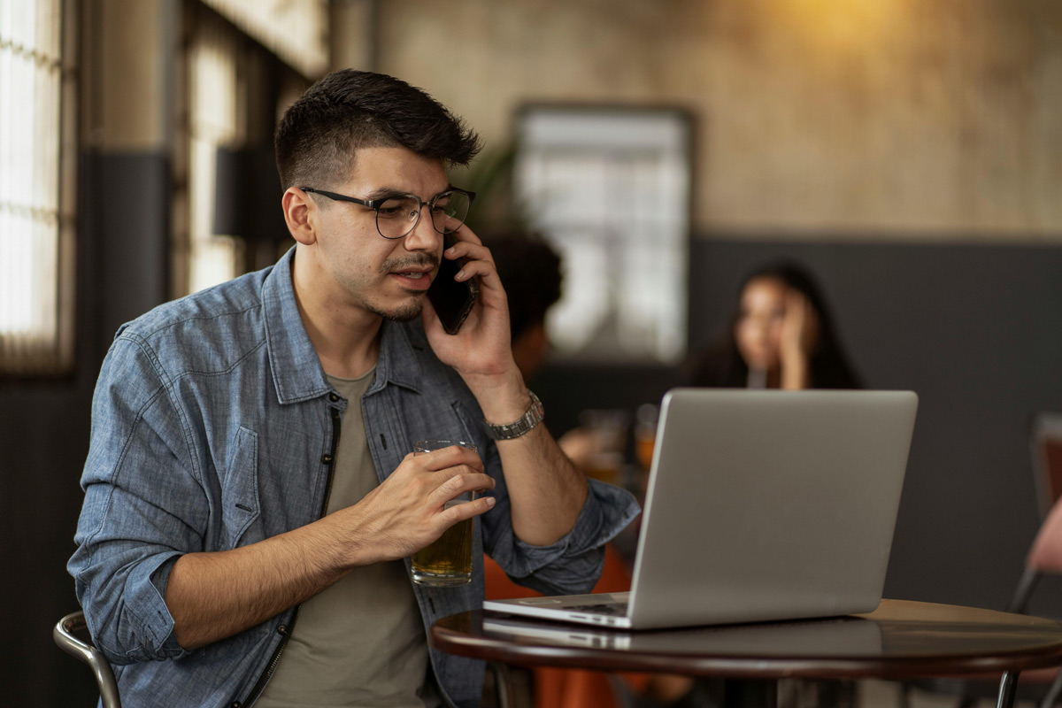 Mann mit Laptop telefoniert in Restaurant